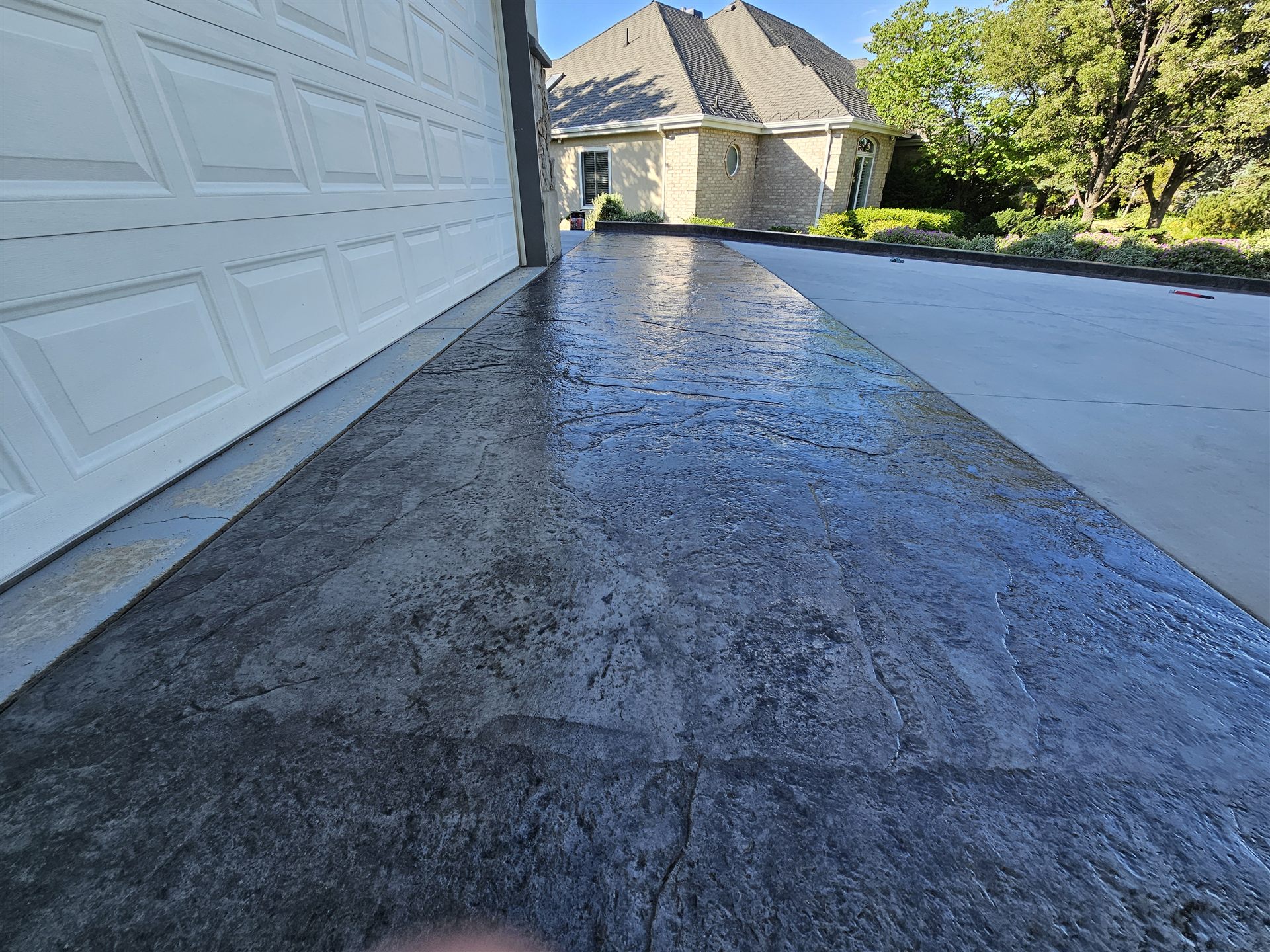 Freshly sealed stamped slate-pattern concrete driveway